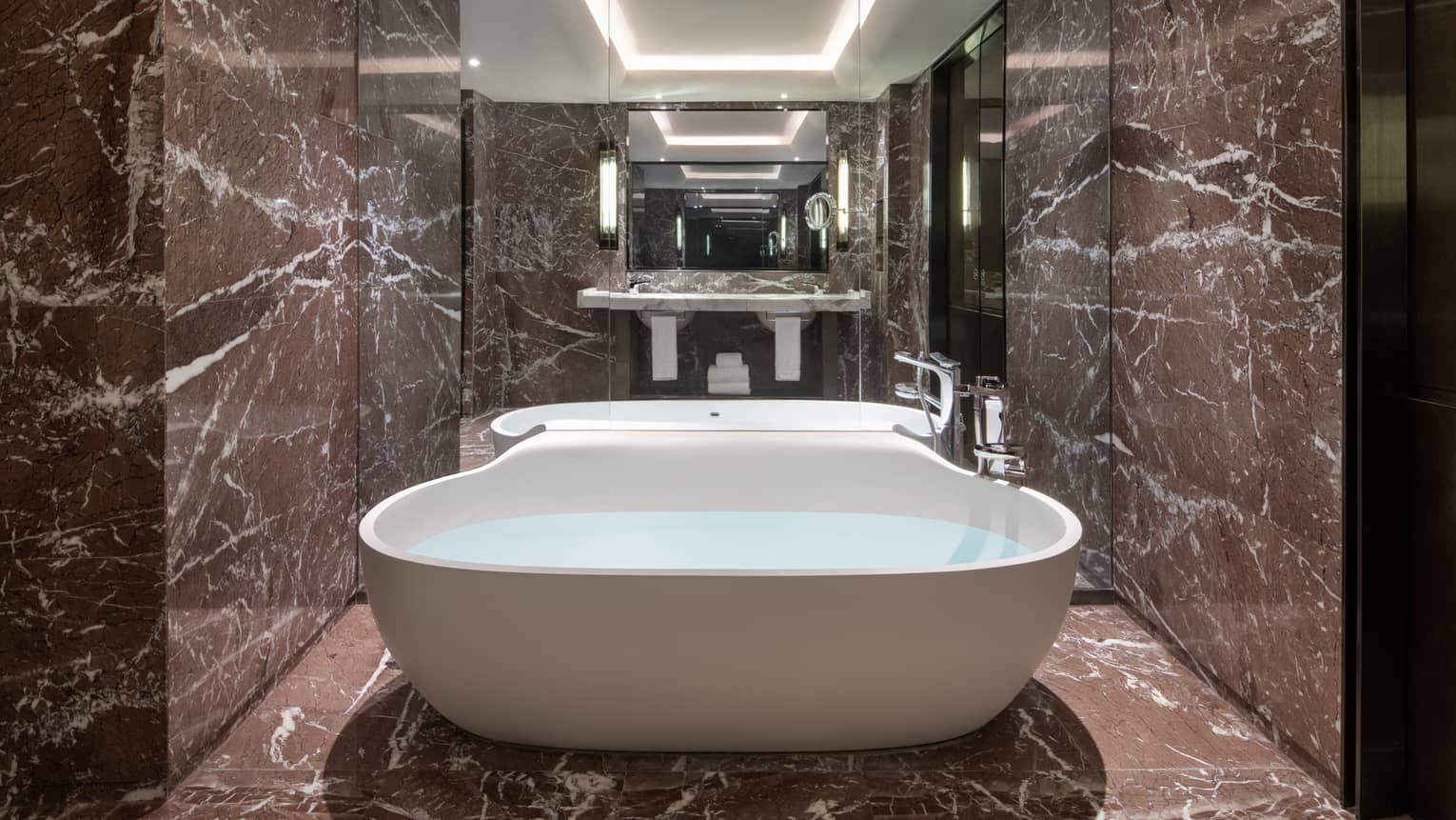 Guest bathroom with chocolate marble, mirrored wall, large soaking tub