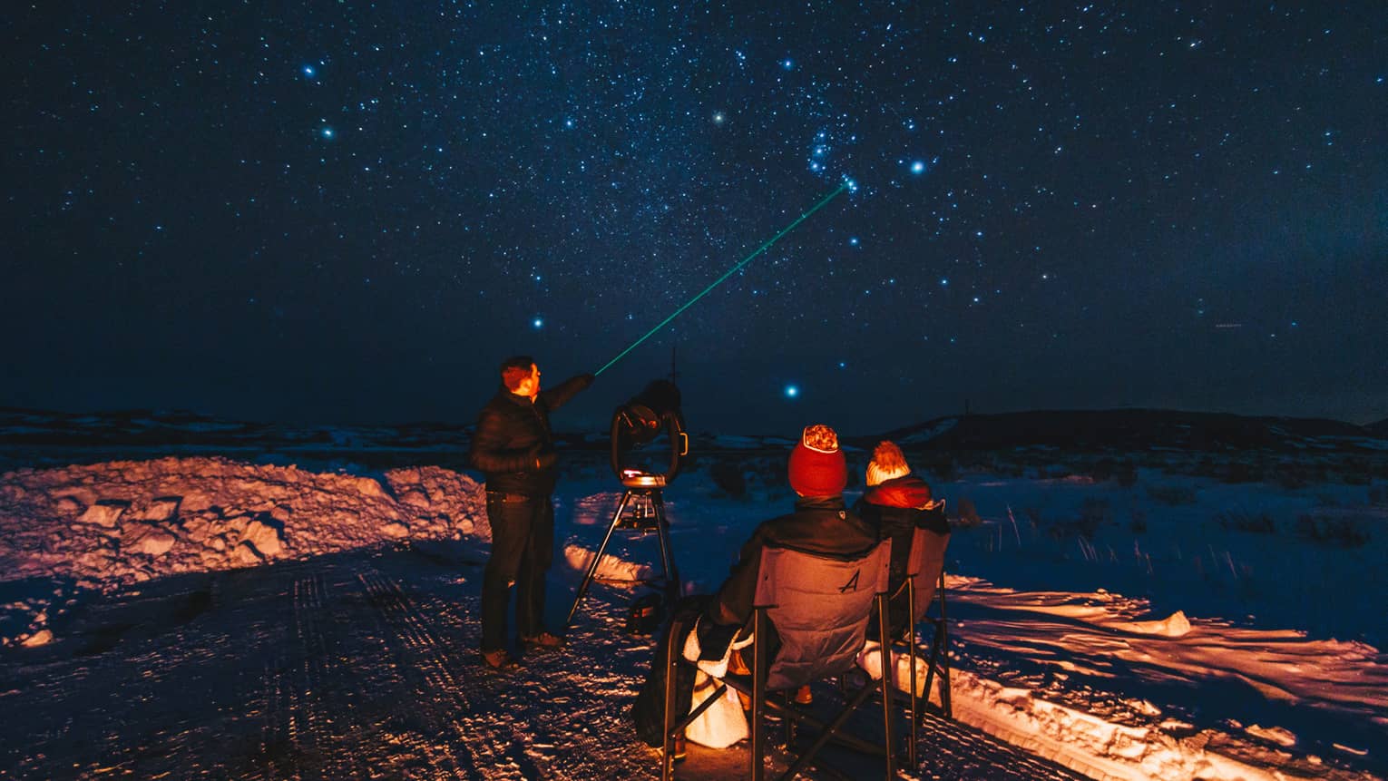 An instructor uses a laser pointer as he identifies constellations for guests
