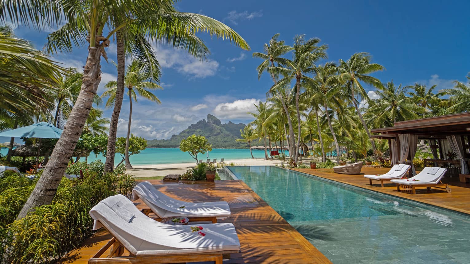 Long rectangular pool with lounge chairs in Bora Bora villa, with view of turquoise lagoon