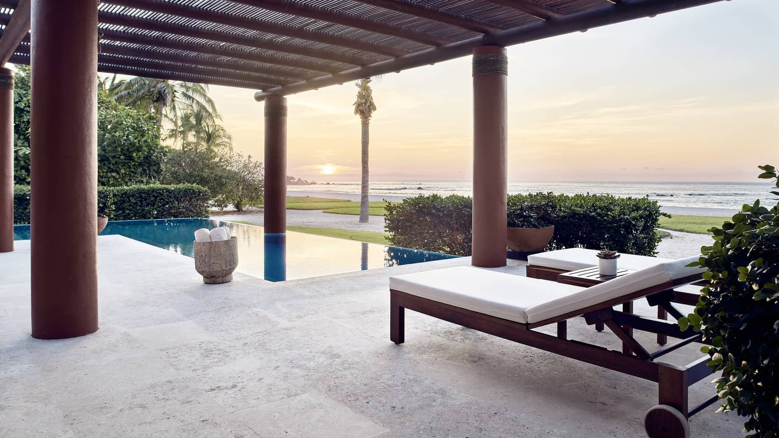Outdoor terrace with lounge chairs, private pool, sun setting over the sea