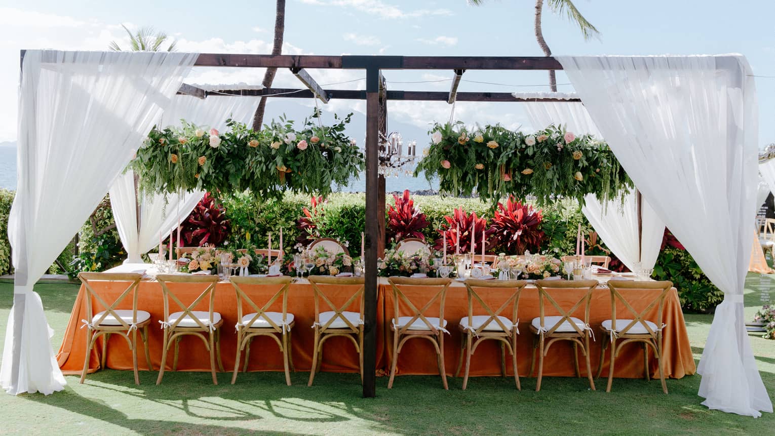Outdoor wedding reception table under pergola with white curtains