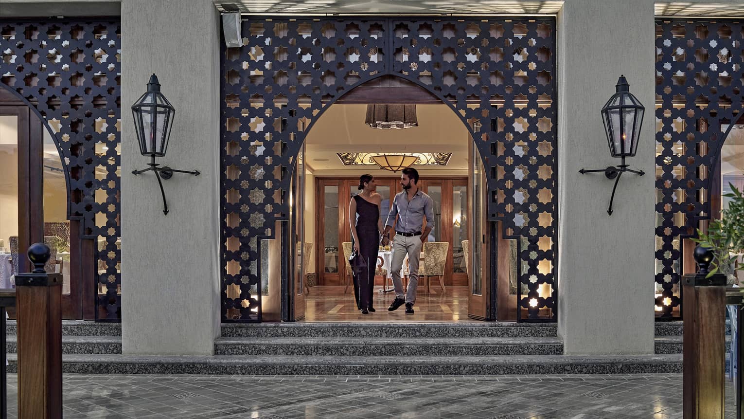 Man and woman walking out of a restaurant with Arabesque detailing around doorway