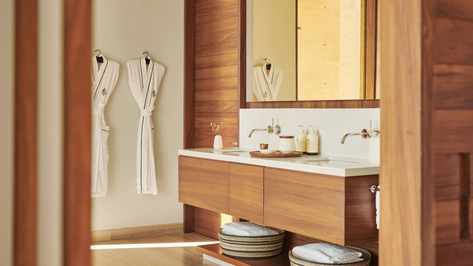Modern bathroom with wood vanity and walls, two hanging bathrobes