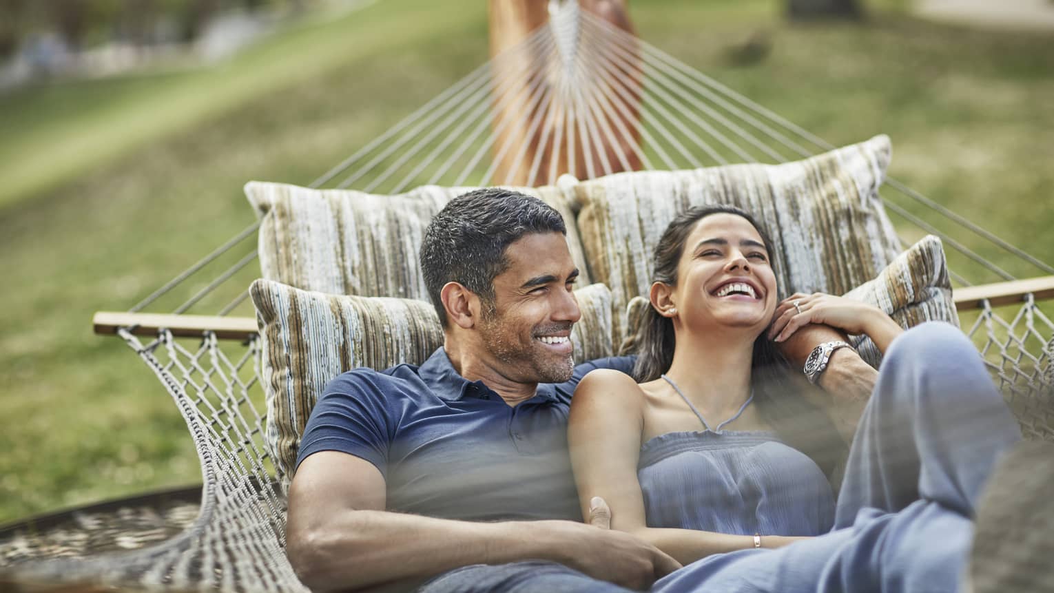 Smiling couple relaxes in hammock on lawn