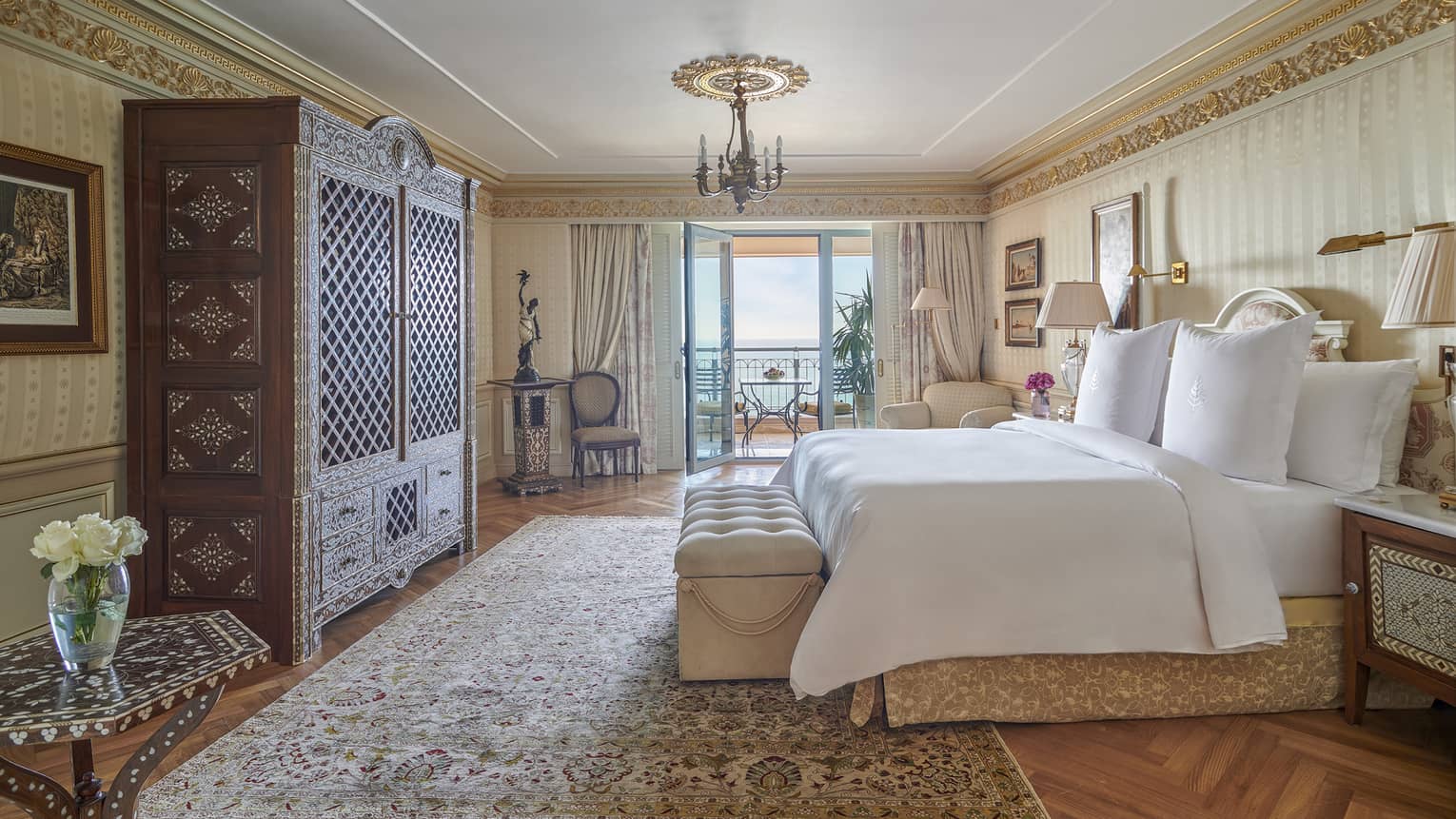 Royal Suite bedroom with king bed, oak armoire, corner armchair, glass door to veranda