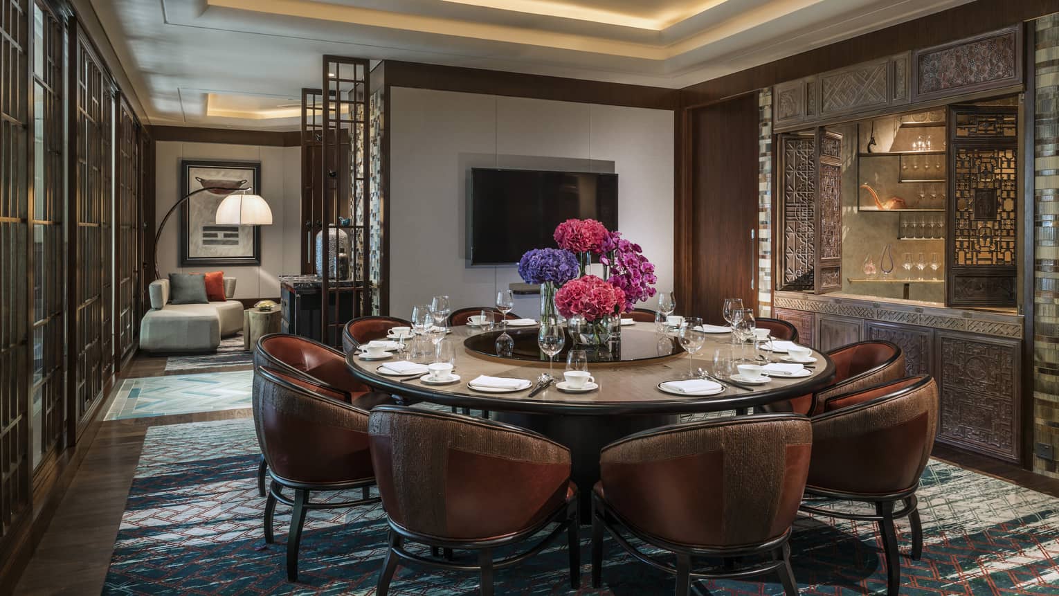 Leather bucket chairs around private meeting dining table, TV on wall