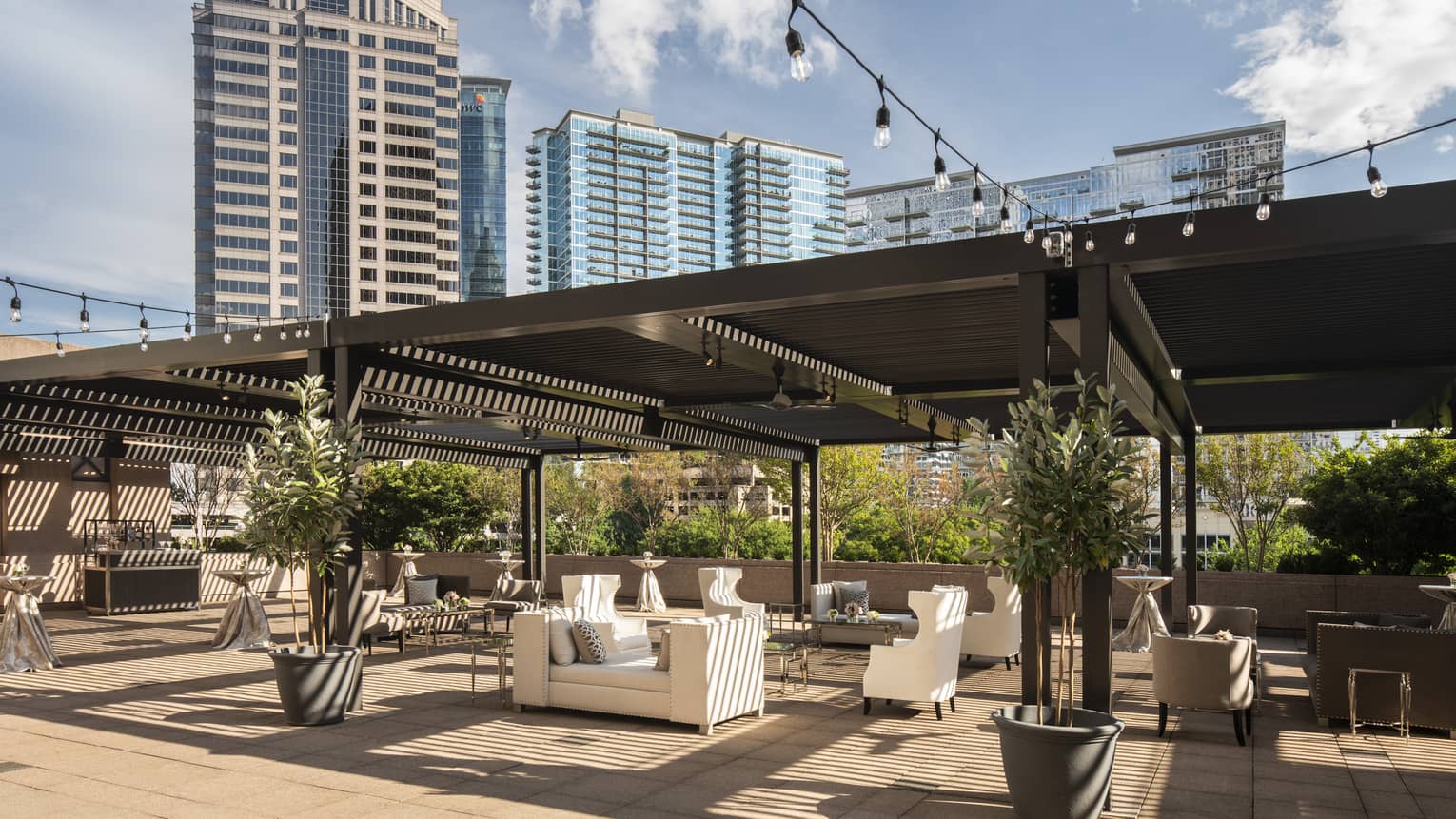 Fifth-floor rooftop terrace during the day with modern white sofas under large wood pergola