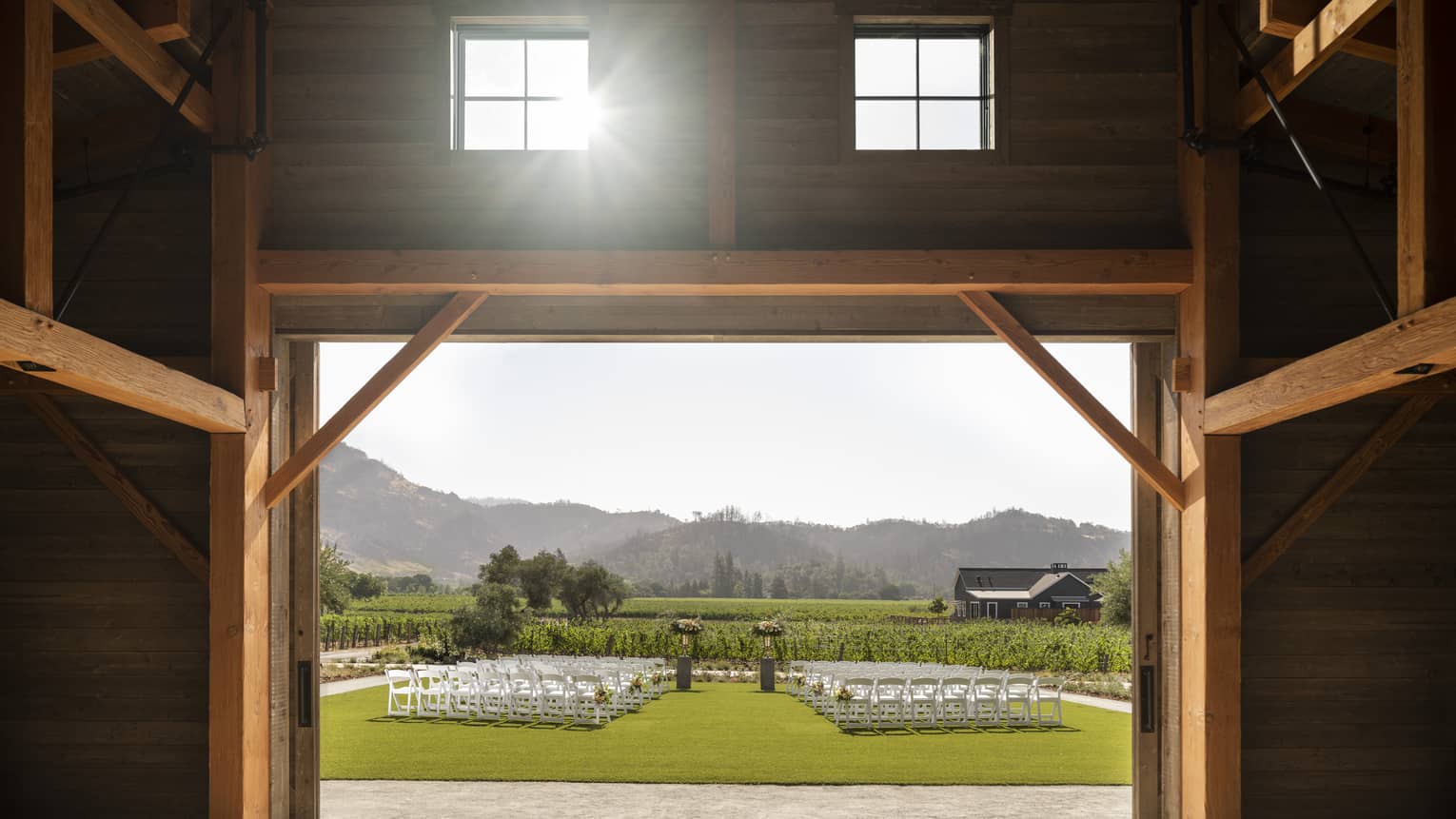 Barn doors opening up to lawn set up for wedding ceremony