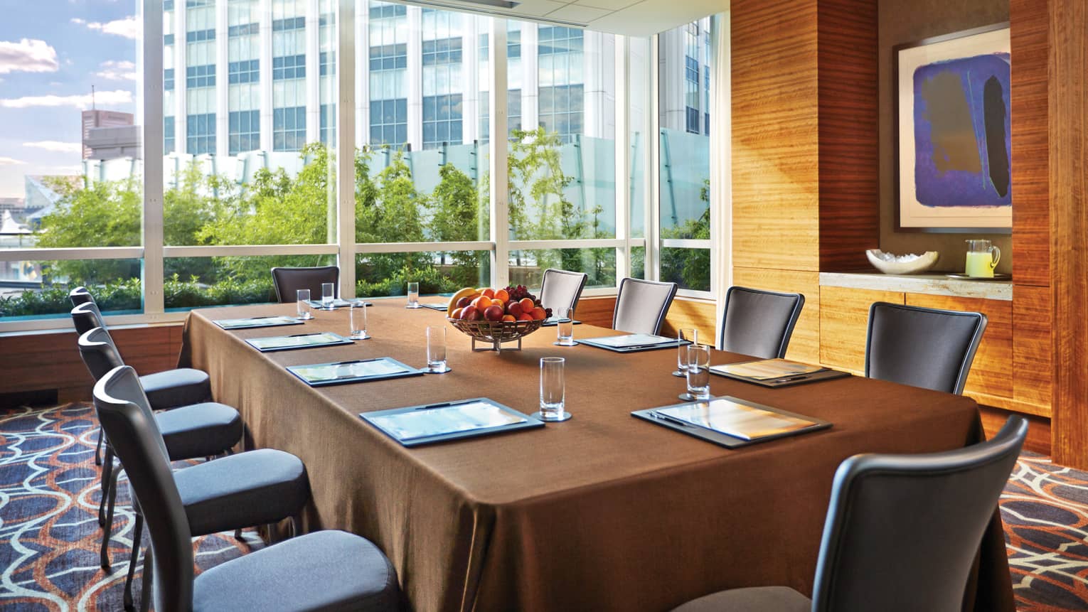 Large rectangular boardroom meeting table by bright floor-to-ceiling window