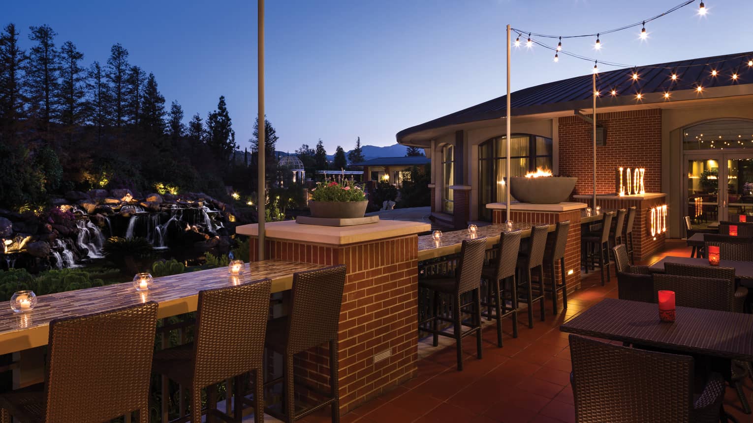 Candle-lit bar, stools along Lookout patio, string of lights, outdoor patio, waterfall views