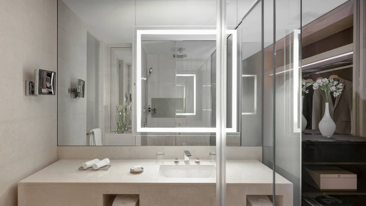 Bathroom with illuminated mirror, glass shower, limestone vanity