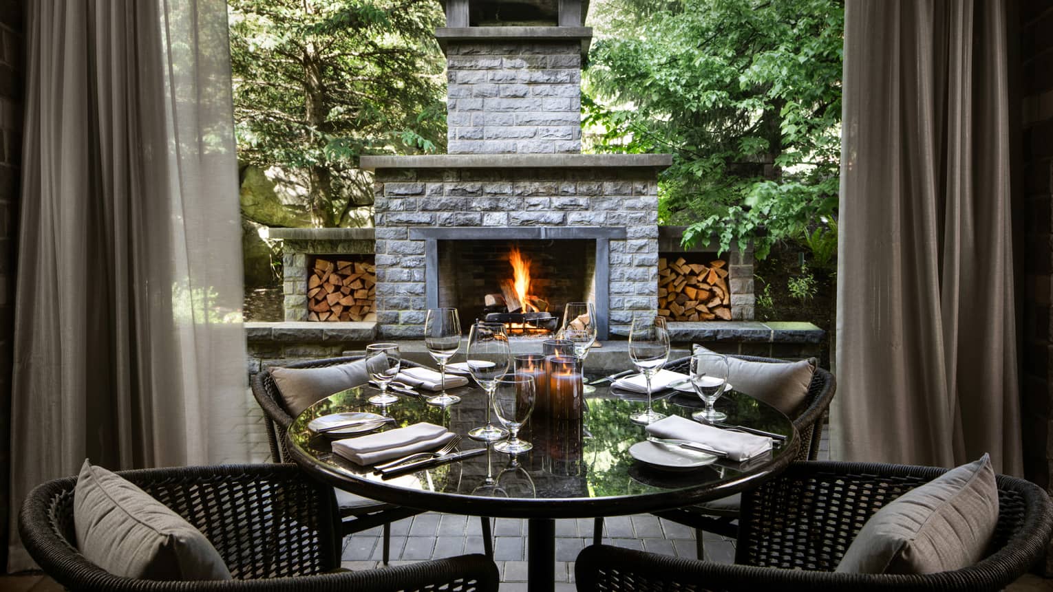 Chairs and tables outside near a stone fireplace.