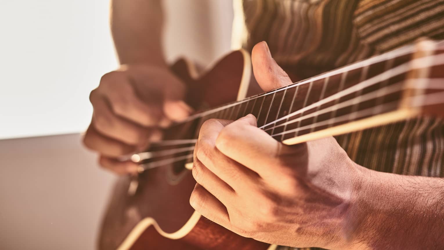 Close-up of hands playing ukulele stringed instrument