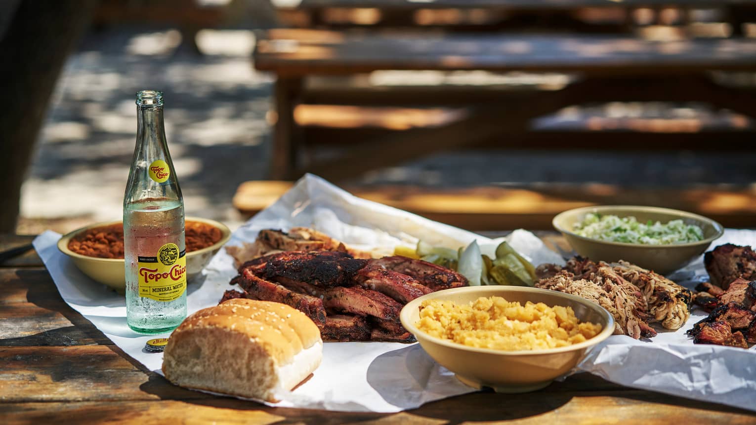 Barbecue meat, salads, glass bottle on picnic tables