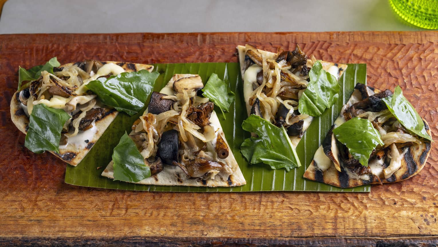 Mushroom fugazzeta cut into four slices and garnished with arugula served on a wooden platter