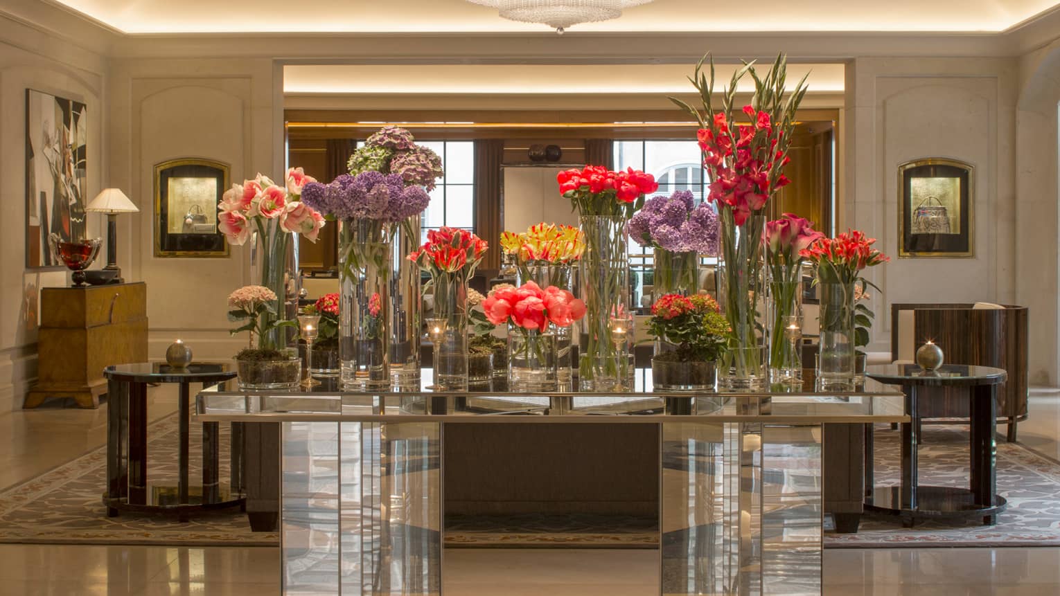 Hotel lobby with multiple crystal vases with flowers of different heights on tabletop
