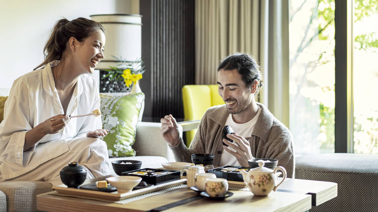 Laughing couple enjoys romantic in-room Japanese breakfast