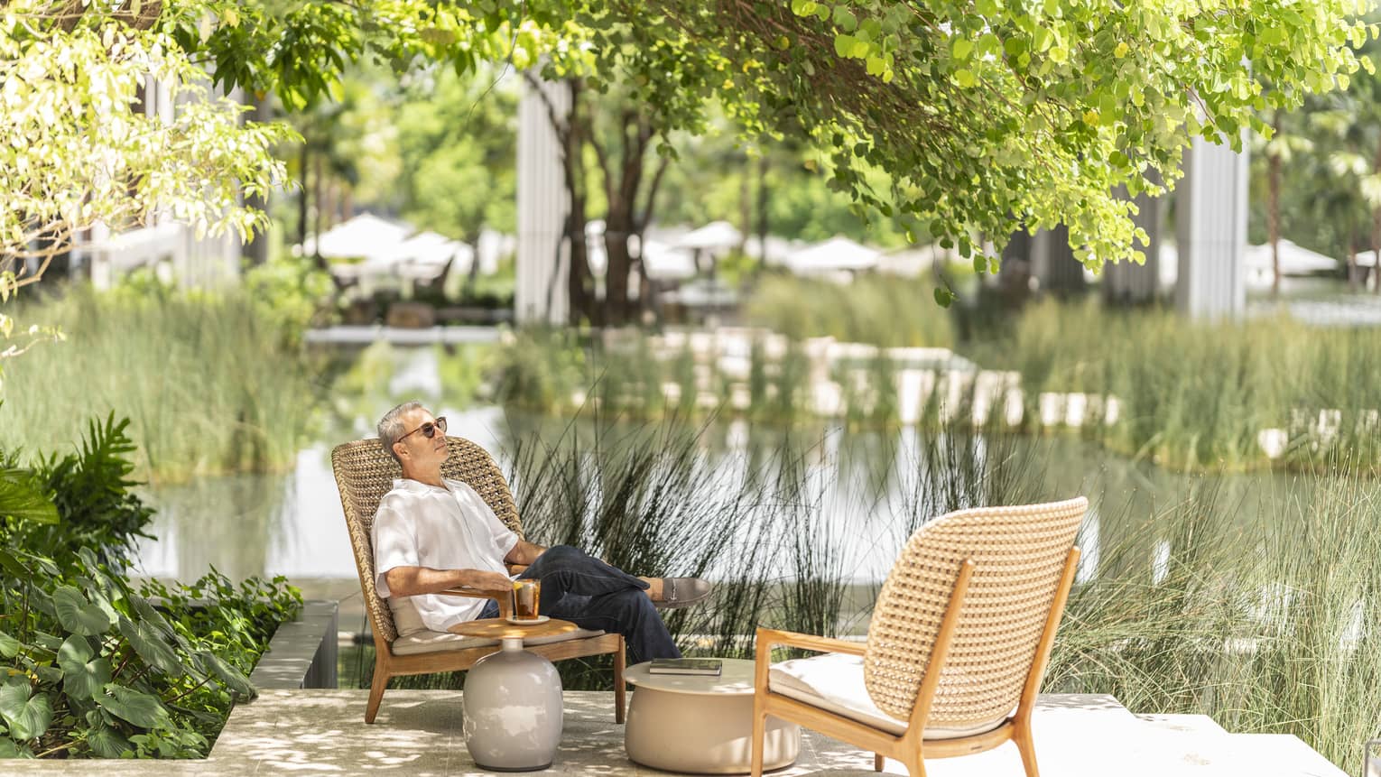 Man lounges in rattan chair by the pond in the Central Courtyard