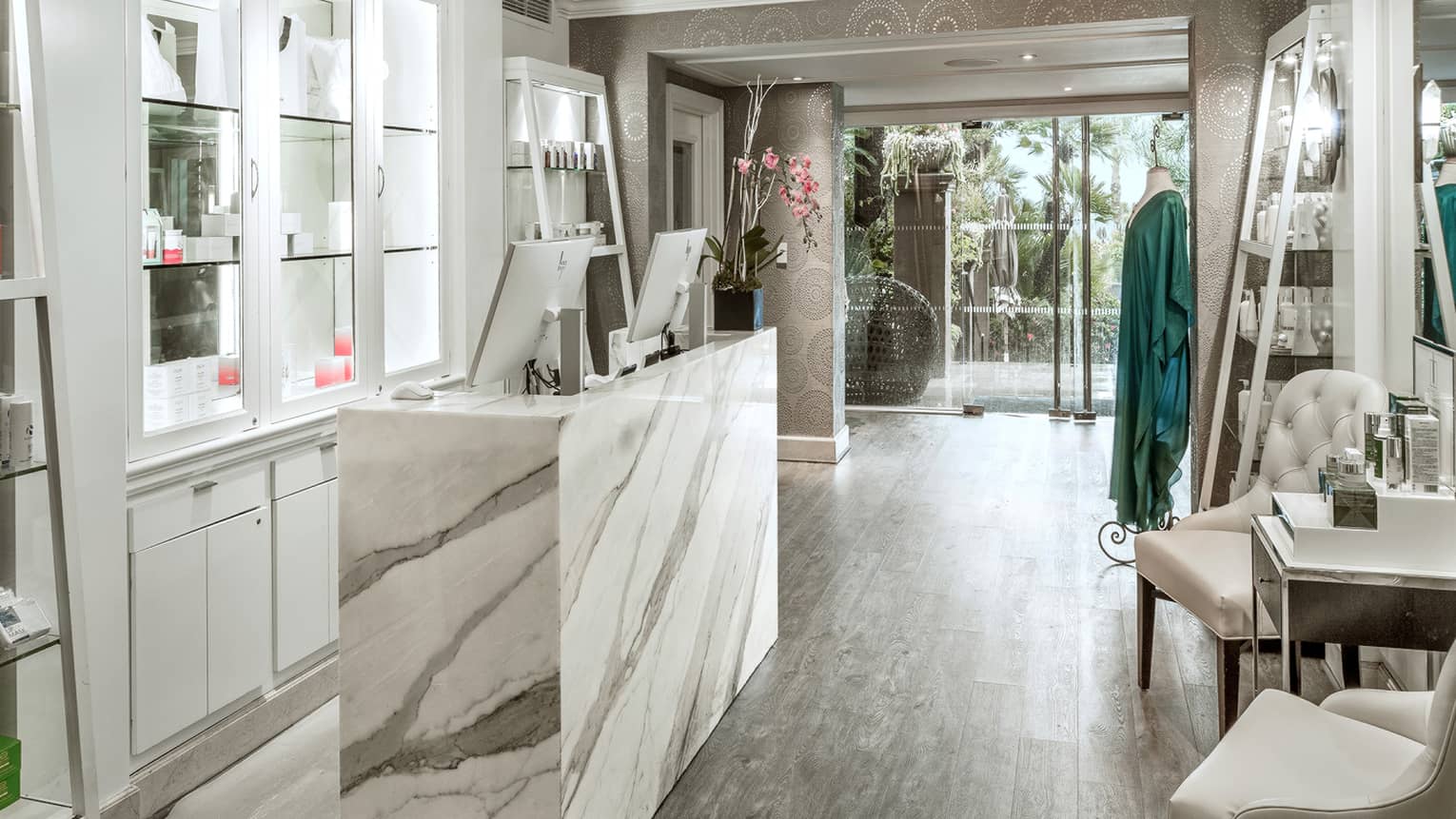 A spa boutique with marble counter, glass cabinets and shelving displaying spa products