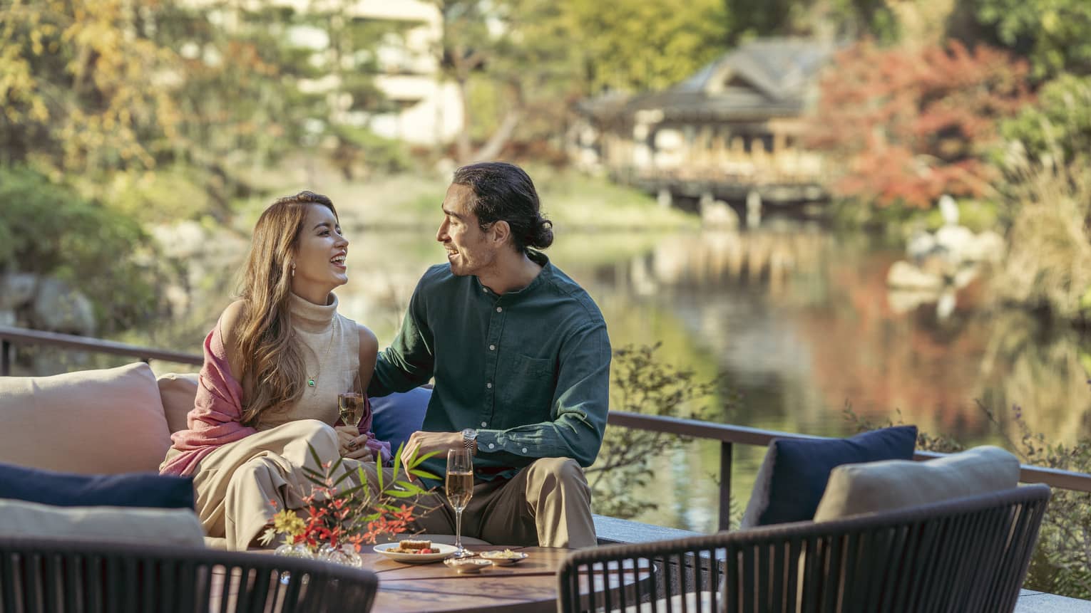 Couple enjoys light snacks and champagne on lounge chair with views of the pond garden