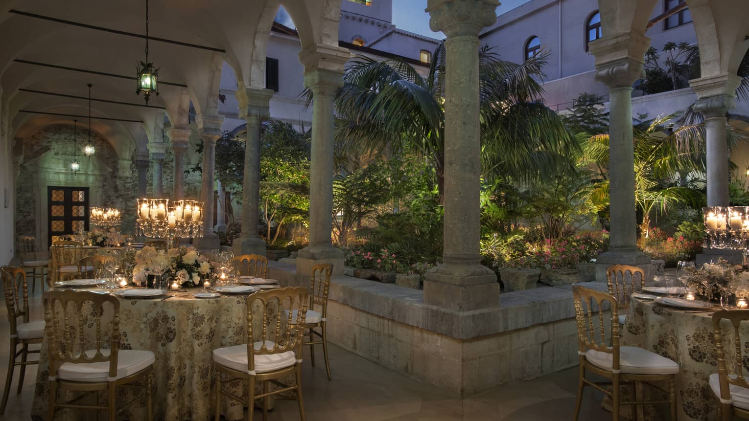 Ancient Cloister outdoor venue with elegant table settings under stone archway at dusk
