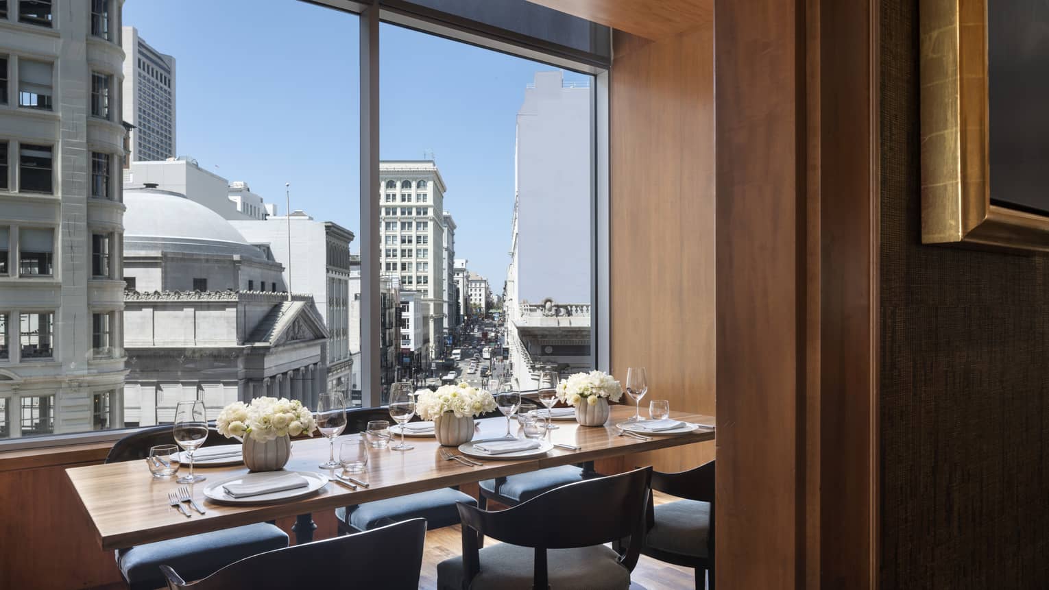 Private dining table with fresh white flowers by sunny window with San Francisco city view 