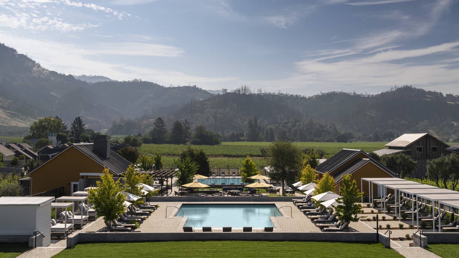 Resort pool in Napa Valley, lined with lounge chairs and mountains in distance