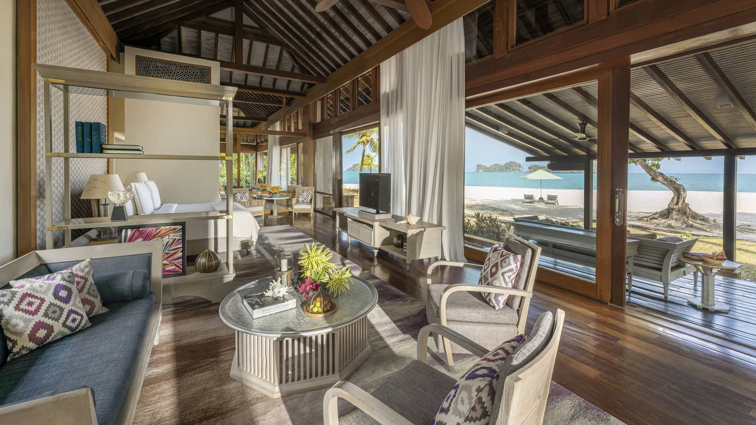 Teak living room opening to covered terrace with beach view