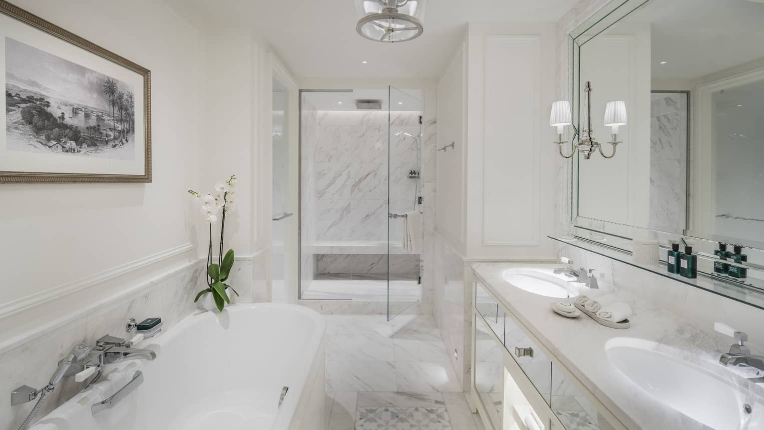 A marble bathroom with a large tub separate from a glass-walled shower.
