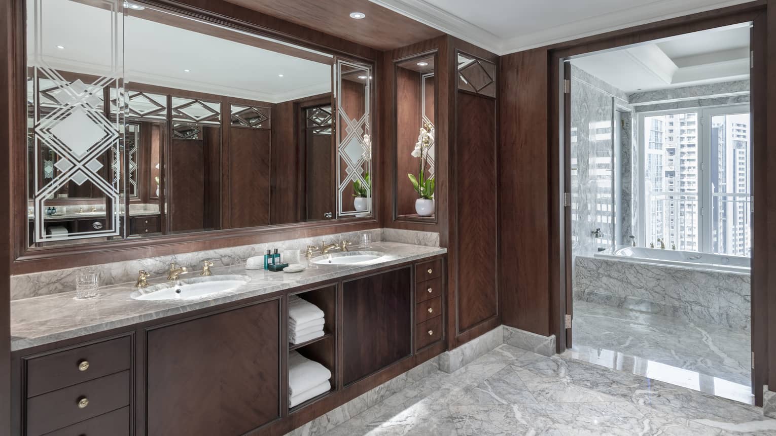 Presidential Suite bathroom featuring dark-wood walls and cabinetry with light-grey marble flooring and vanity counter