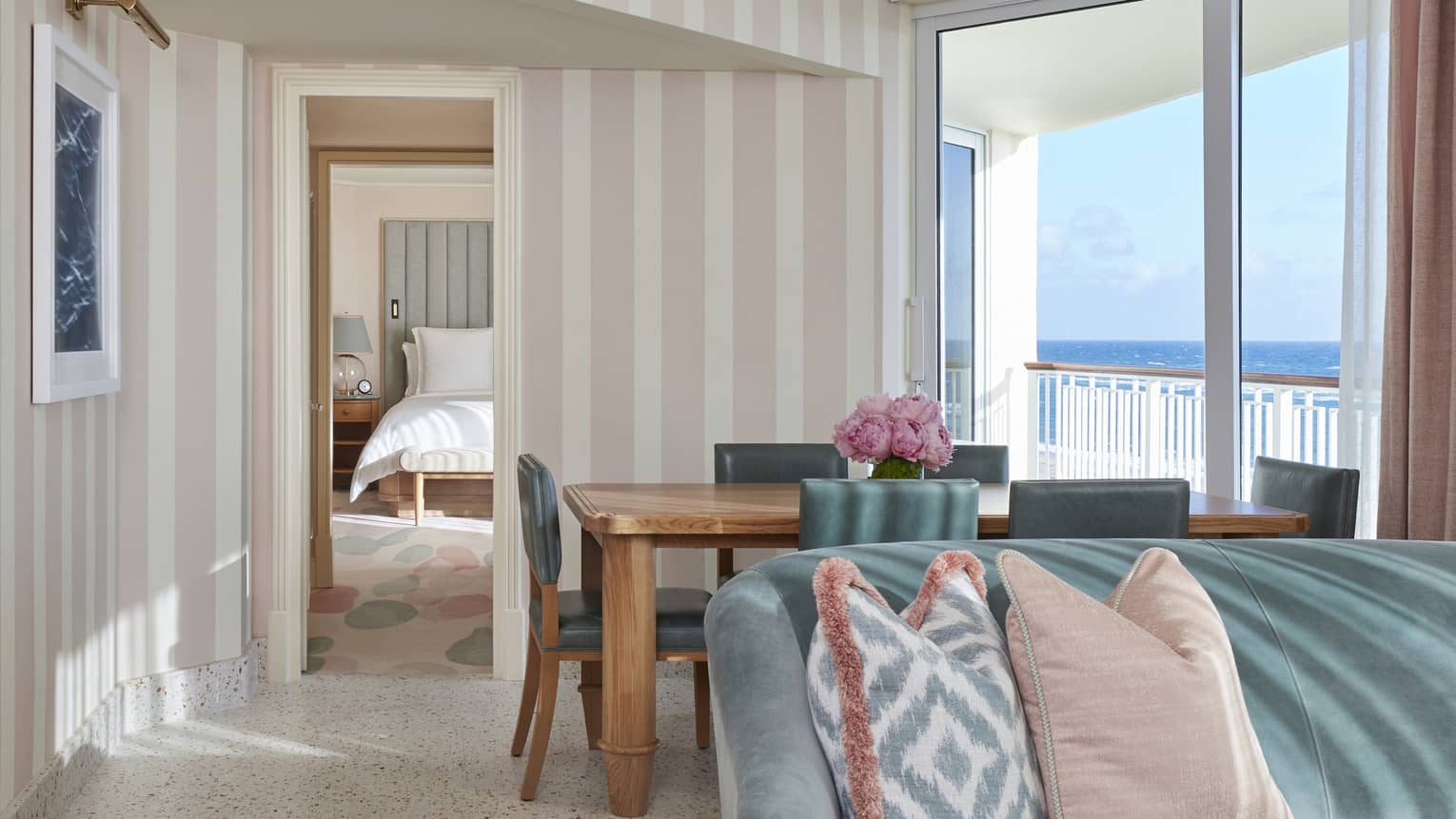 Ocean Grand Suite's living area, featuring a sofa, dining table and light pink- and white-striped walls
