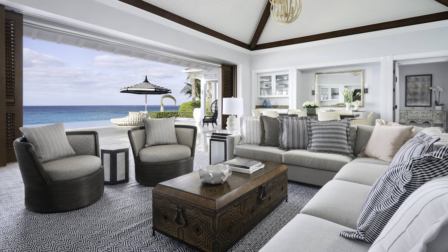 Beachfront Villa Residence large living room with modular sofa, armchairs by open wall to patio overlooking ocean  