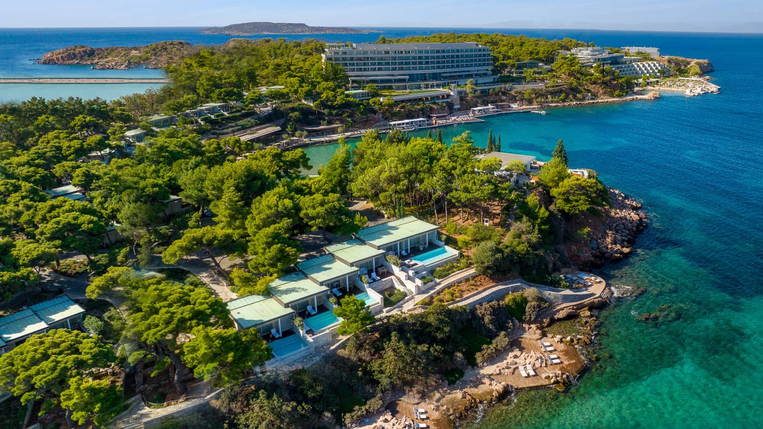 An aerial view of Four Seasons Astir Palace Hotel Athens amid greenery and overlooking the blue-green sea