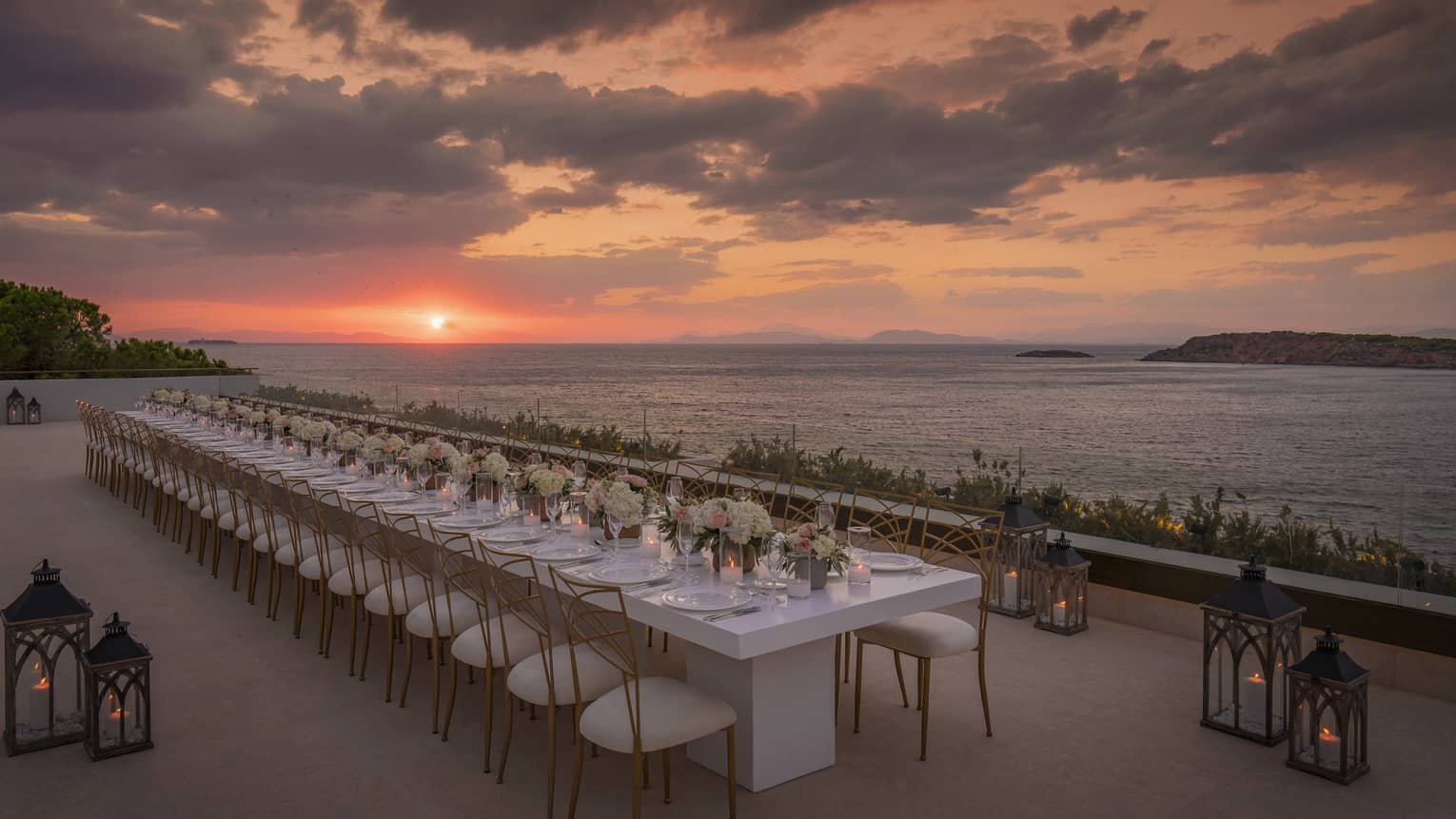 Sunset view over a beautifully arranged outdoor dining setup at Four Seasons Hotel Athens, with elegant table settings and scenic sea views.