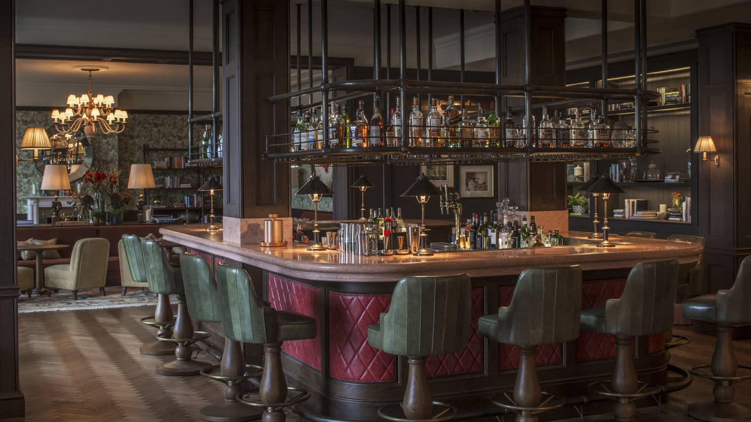 The Bar at Wild Carrot with red-wrapped and wood-accented bar, green barstools, and suspended spirits