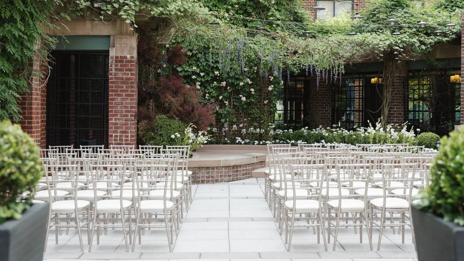 An outdoor venue with rows of white seats and greenery.