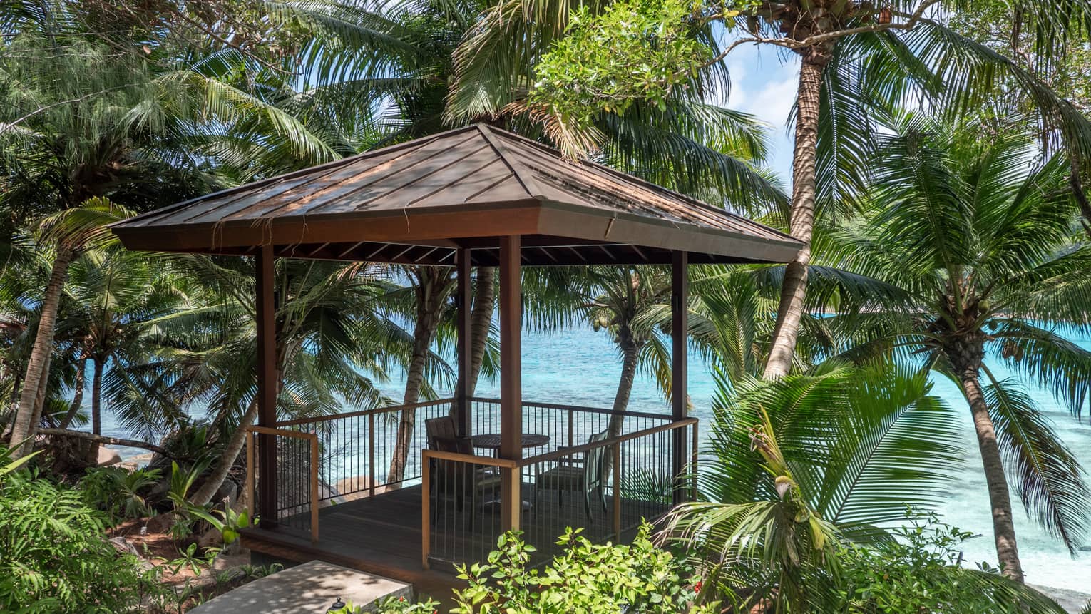 Small pavilion with a table and two chairs at a tropical point overlooking the beach