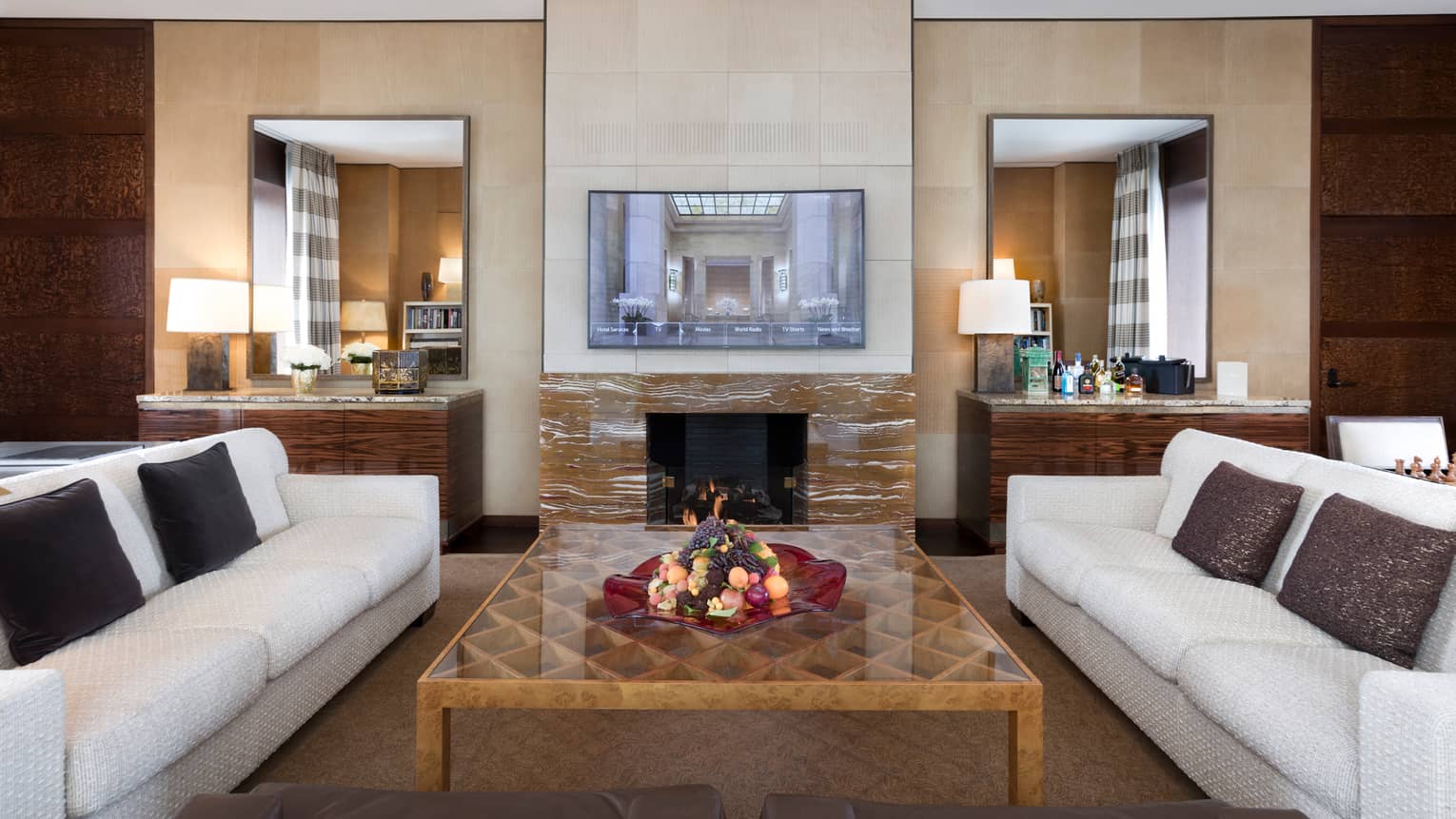Presidential Suite white sofas around large table, wood-grain marble fireplace, TV on mantle