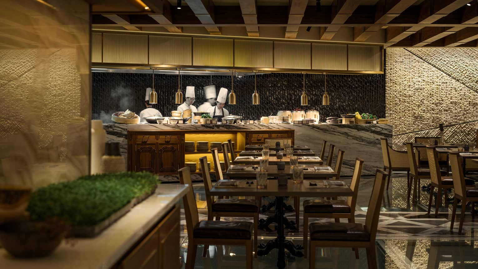 The Market Kitchen dining room tables, chairs in front of white marble counter, chefs at open kitchen