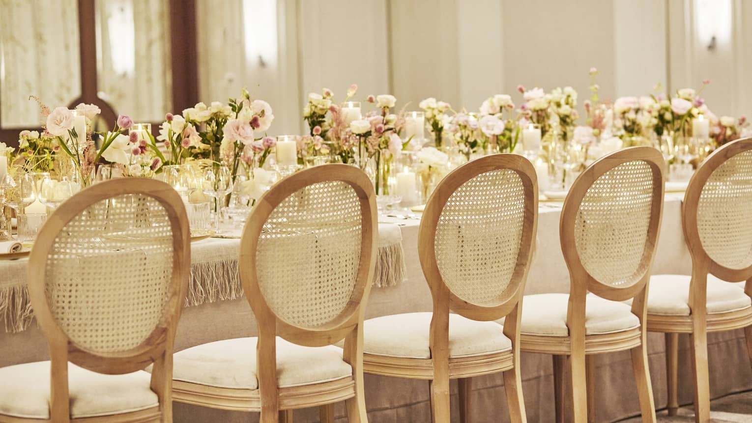 Elegantly set dining table with floral arrangements down centre and lined with chairs