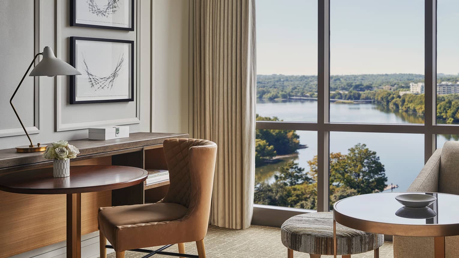 Leather chair by small hotel dining table, floor-to-ceiling windows, Lady Bird Lake views
