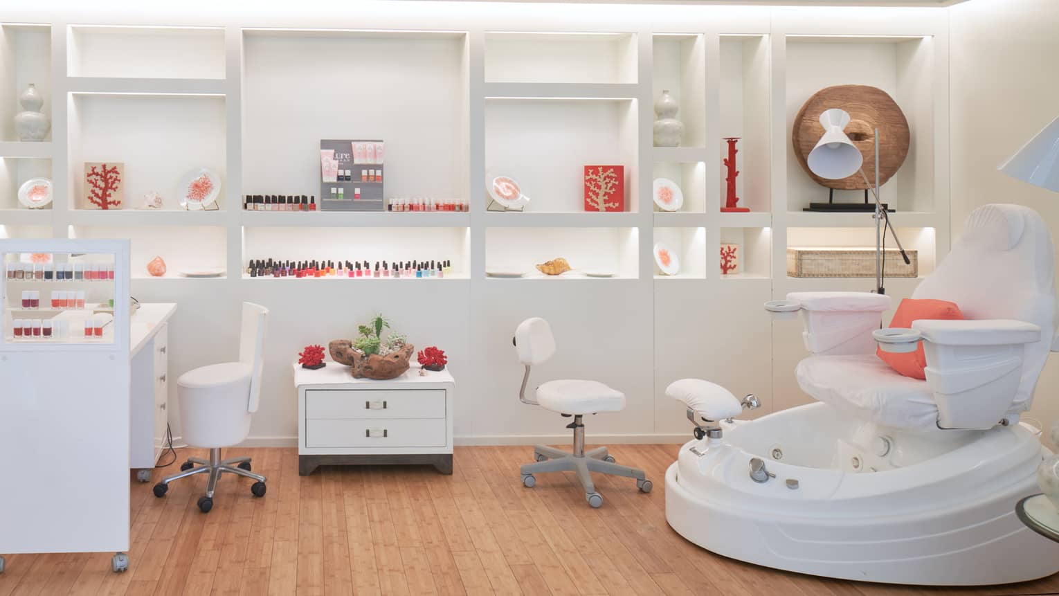 Spa nail bar with manicure station and polish, white wheeled stools, spa pedicure chair, shelving in back