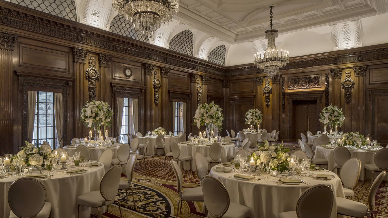 Elegant ballroom with decorative wood walls, crystal chandeliers over round banquet dining tables