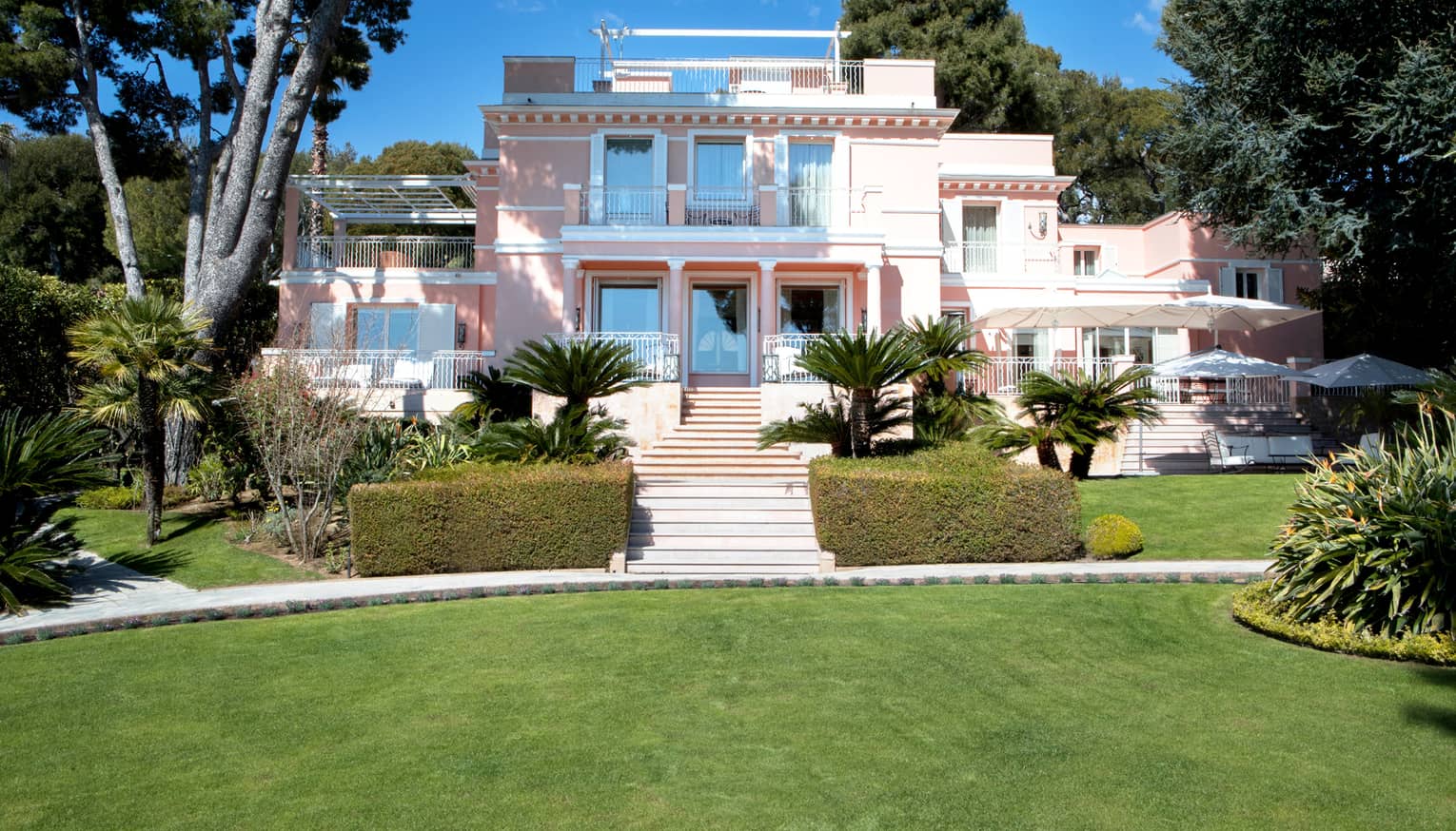 Manicured gardens, steps up to large three-storey pink Villa Rose-Pierre