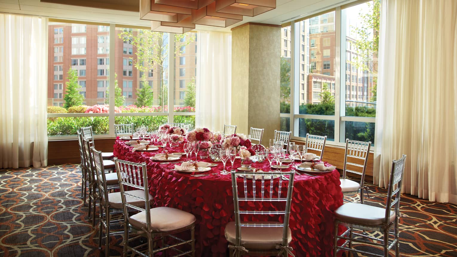 Verona room, round private dining table with red ruffled linen, bright corner windows