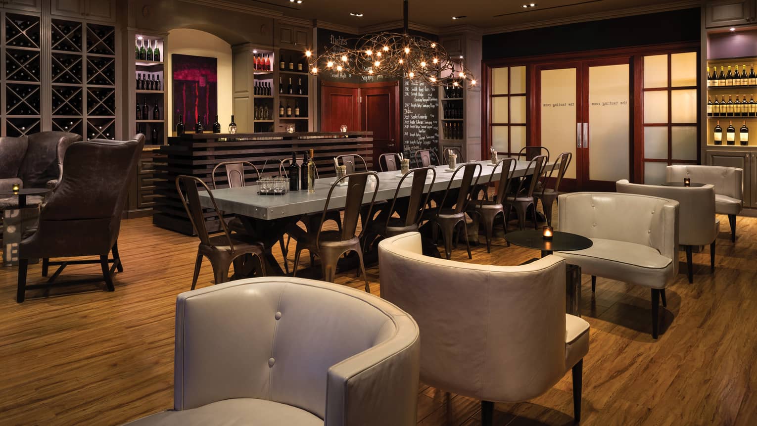 The Tasting Room leather chairs around long, industrial-style steel tasting table under lamp