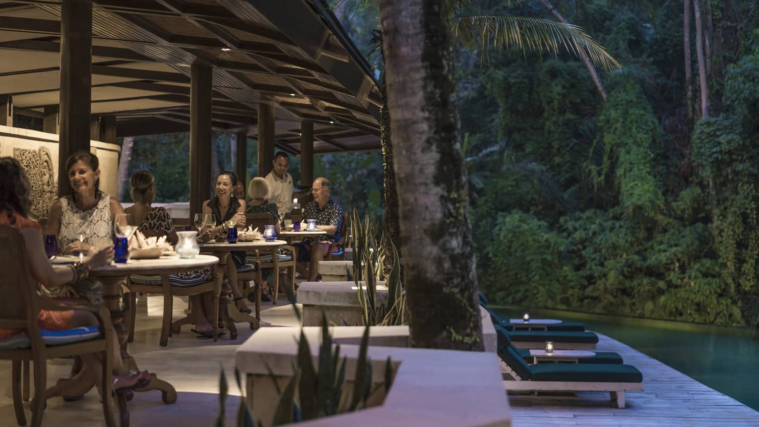 Guests enjoying dinner adjacent to a river in Bali