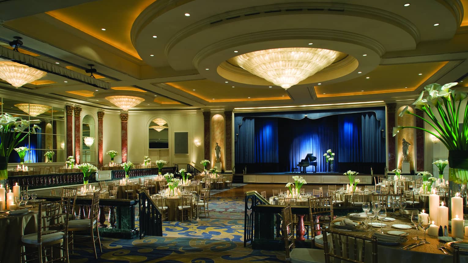 Cone shaped chandelier and round ceiling over banquet room dance floor by stage with baby grand piano, blue lights