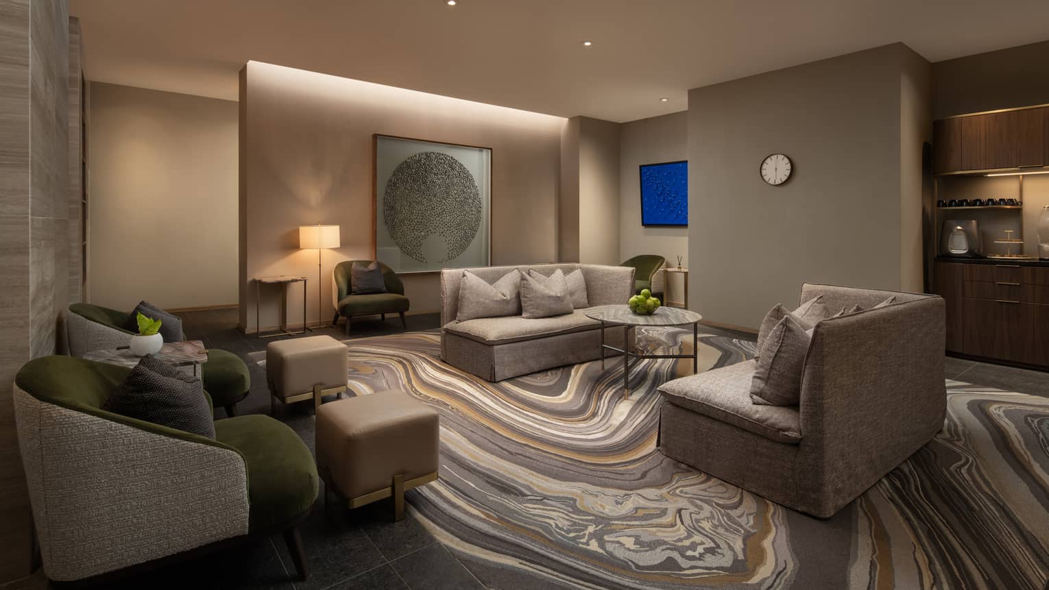 Relaxation lounge area with grey sofas and armchairs, marble-patterned carpet and intimate lighting