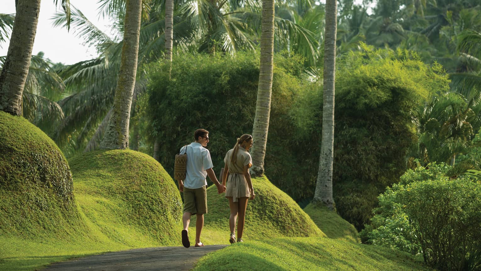 Guests holding hands and strolling through a garden in Bali